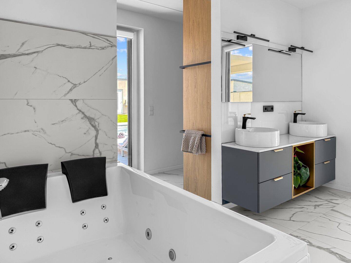 Modernes Badezimmer mit Whirlpool-Badewanne, Doppelwaschbecken und Zugang zum Außenbereich mit Pool.