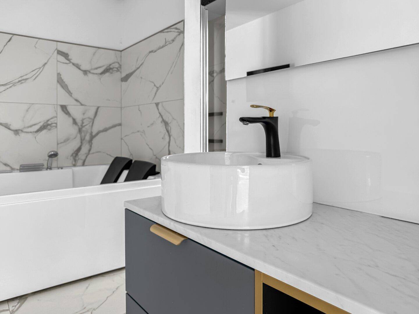 Detailaufnahme des modernen Doppelwaschbeckens mit schwarzem Wasserhahn und Marmoroptik-Fliesen.