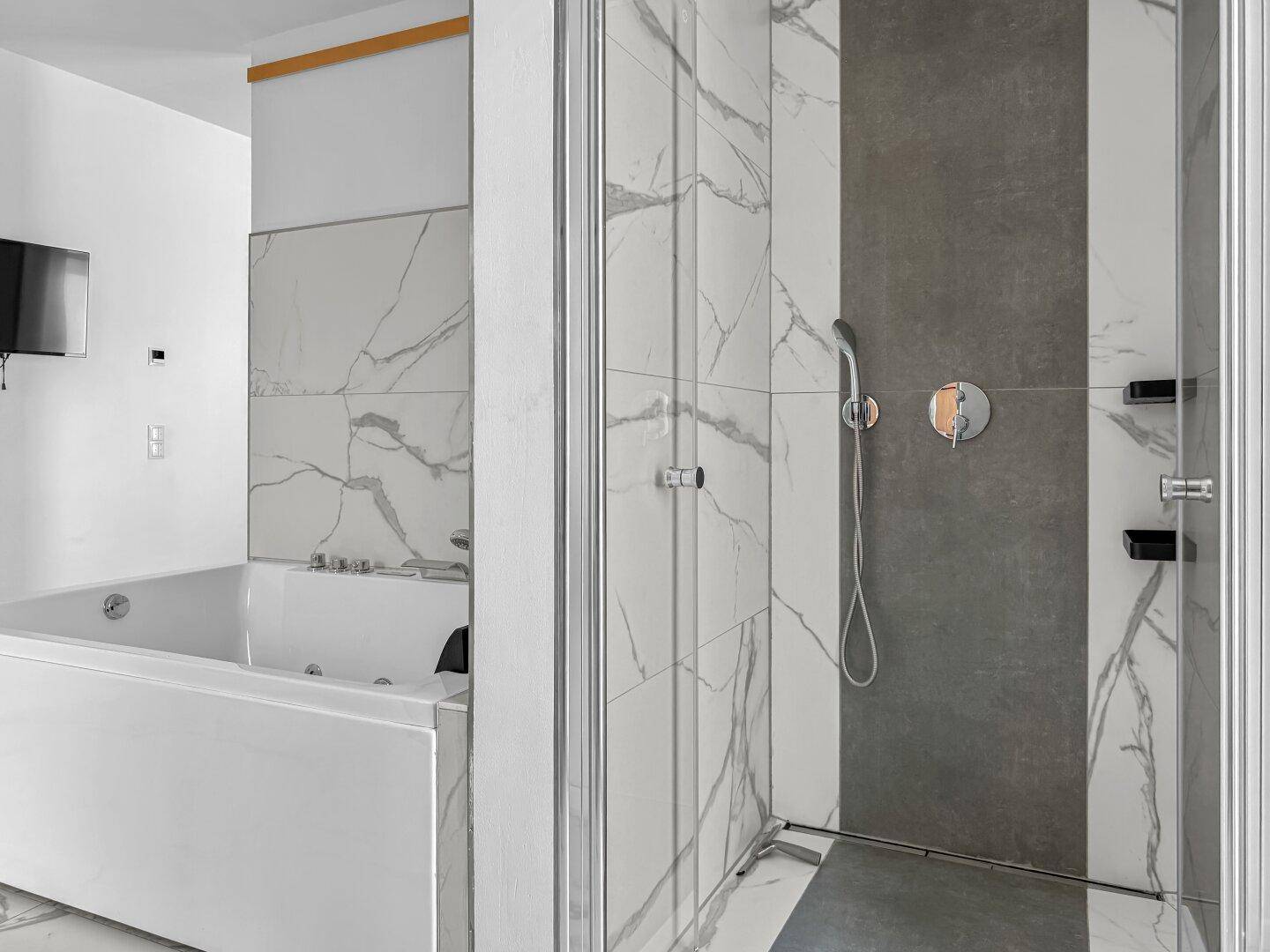 Modernes Badezimmer mit großer Duschkabine, Whirlpool-Badewanne und eleganten Marmoroptik-Fliesen.