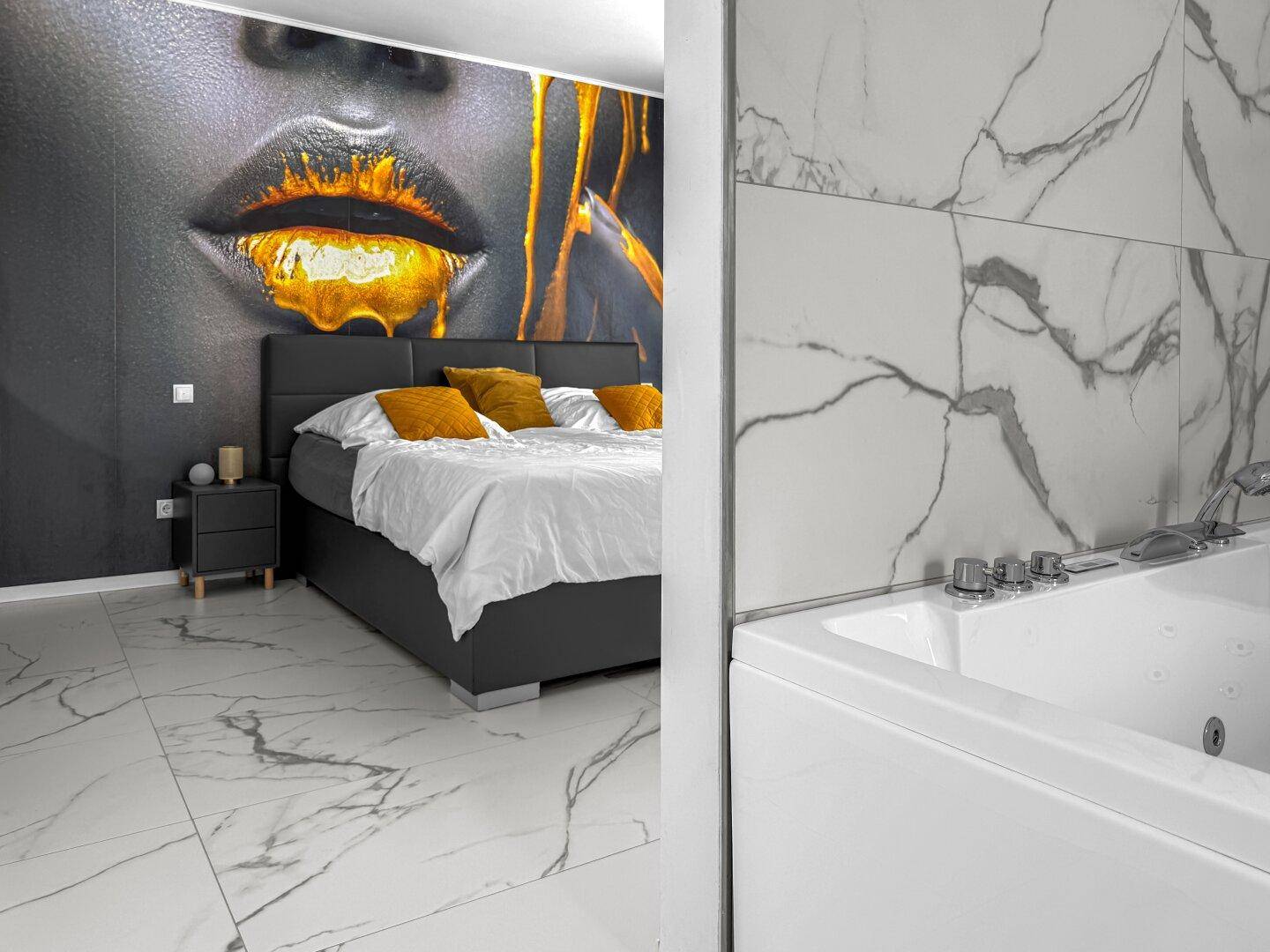 Modernes Badezimmer mit Badewanne und offenem Übergang zum Schlafzimmer mit Wandmalerei.