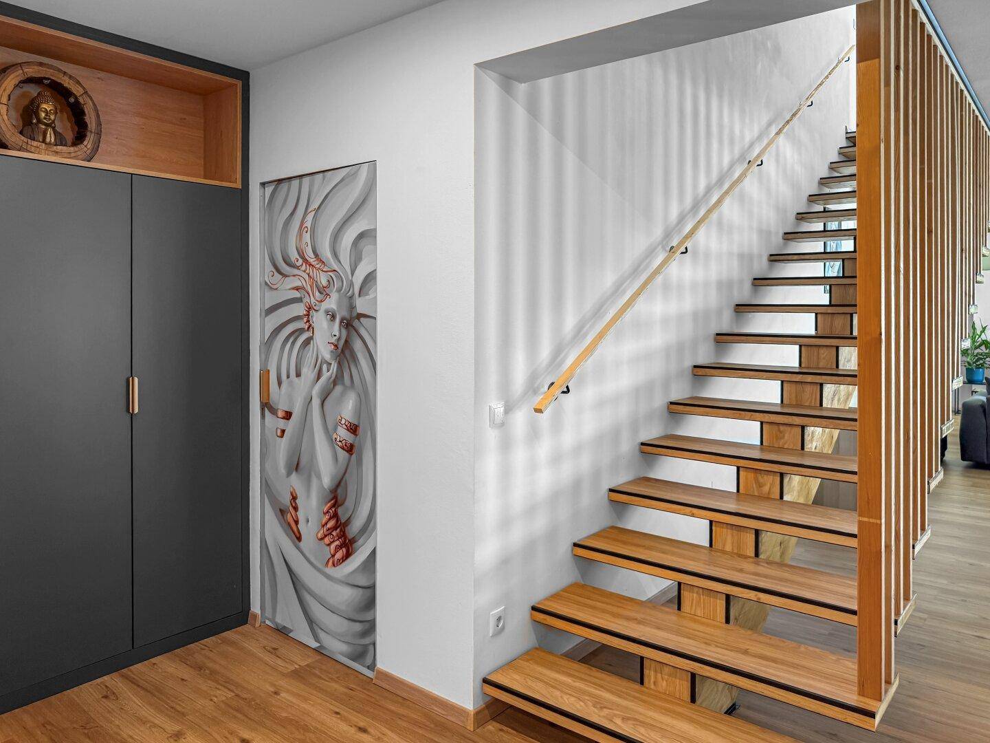 Moderner Eingangsbereich mit Holztreppe, integrierten Schränken und dekorativer Wandkunst.