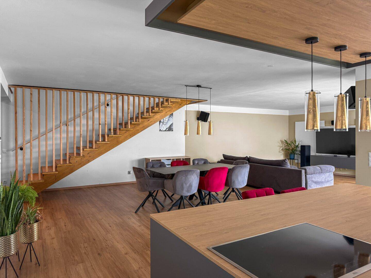 Offener Wohn- und Essbereich mit Holzboden und einer eleganten Holztreppe zum Obergeschoss.