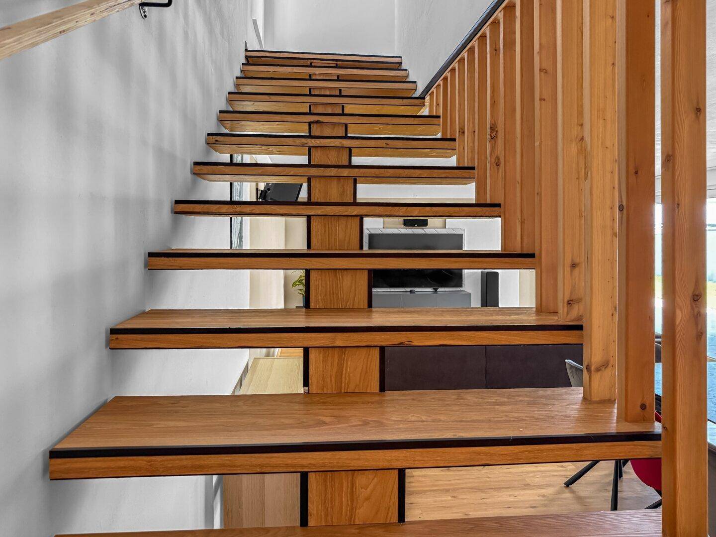 Elegante Holztreppe mit offener Bauweise und modernem Geländer, die die Etagen verbindet.