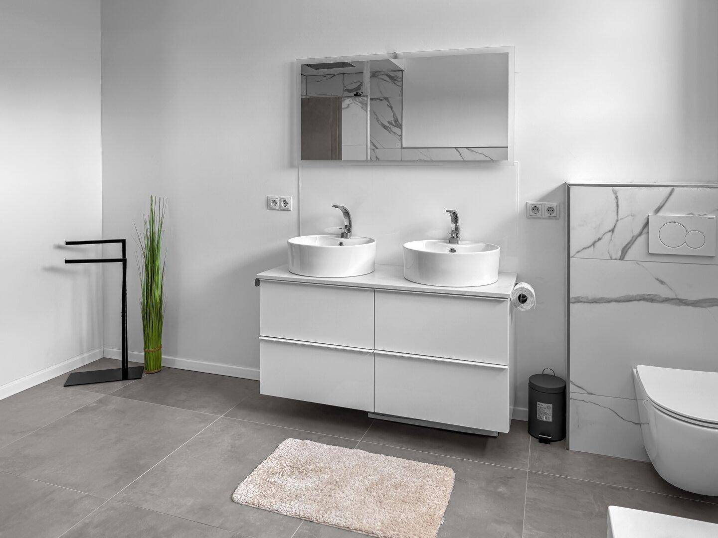 Modernes Badezimmer mit Doppelwaschbecken, Wand-WC und großformatigen Fliesen.