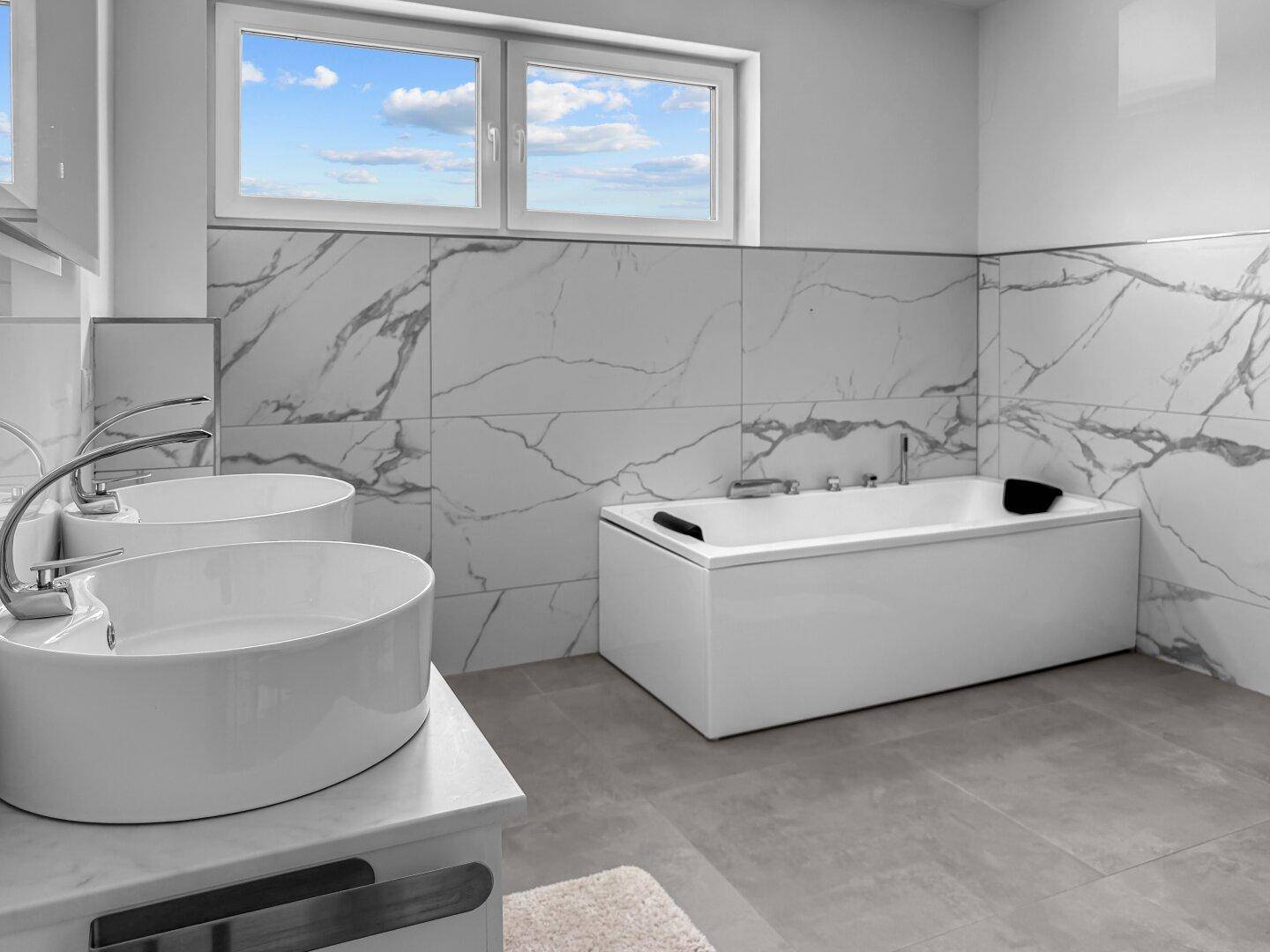 Modernes Badezimmer mit Badewanne, Doppelwaschbecken und großen Fenstern.