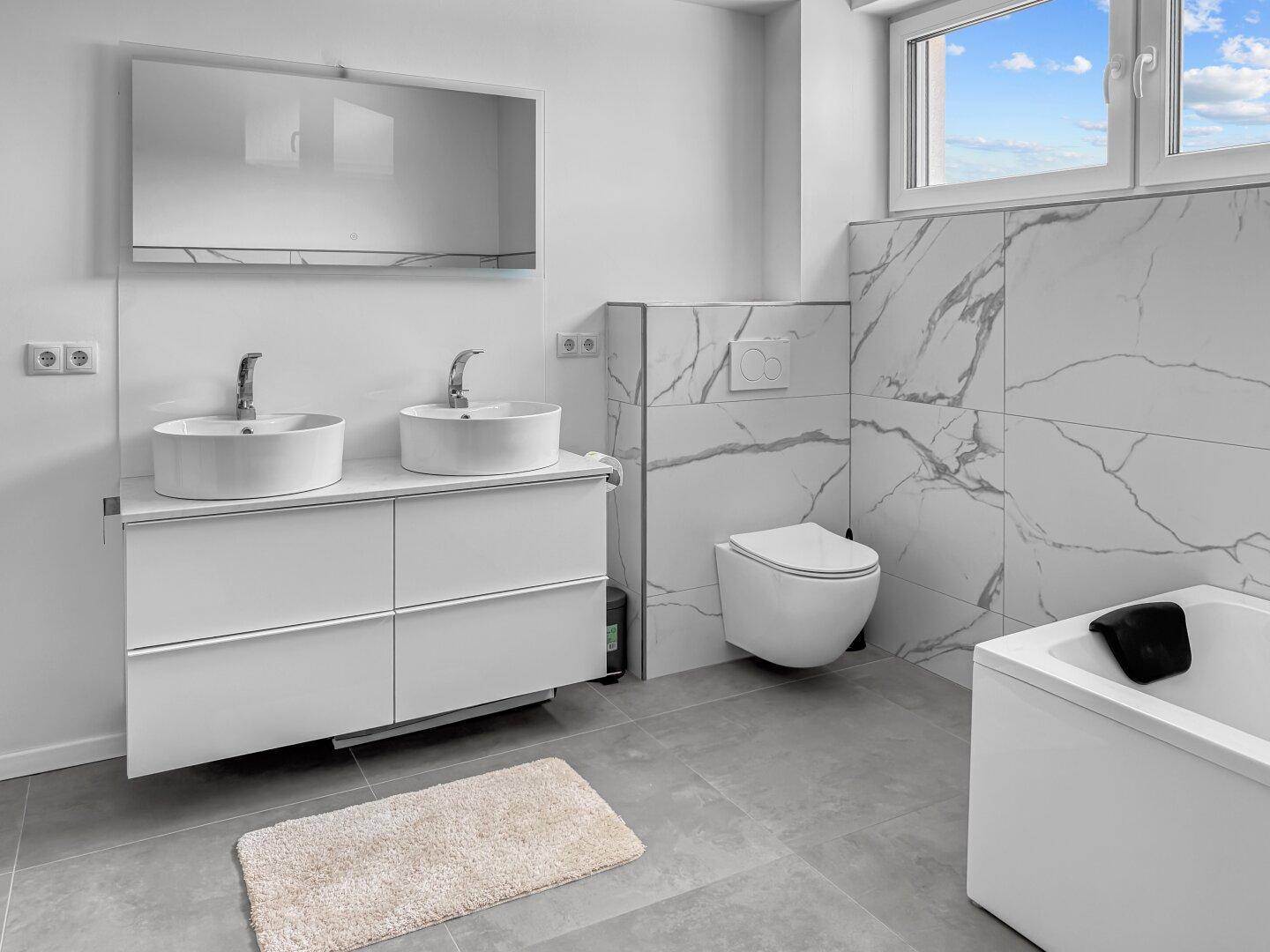 Modernes Badezimmer mit Doppelwaschbecken, Wand-WC und Badewanne, hell und geräumig.