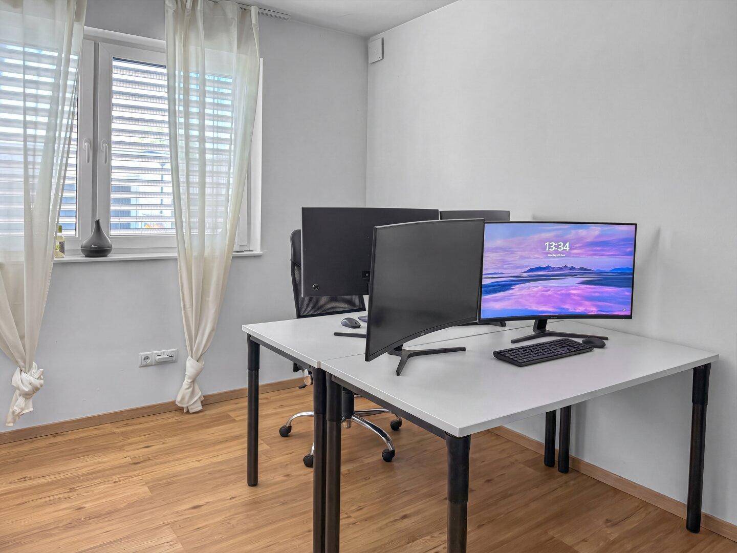 Helles Heimbüro mit zwei Arbeitsplätzen, Holzfußboden und Fenster mit Jalousien.