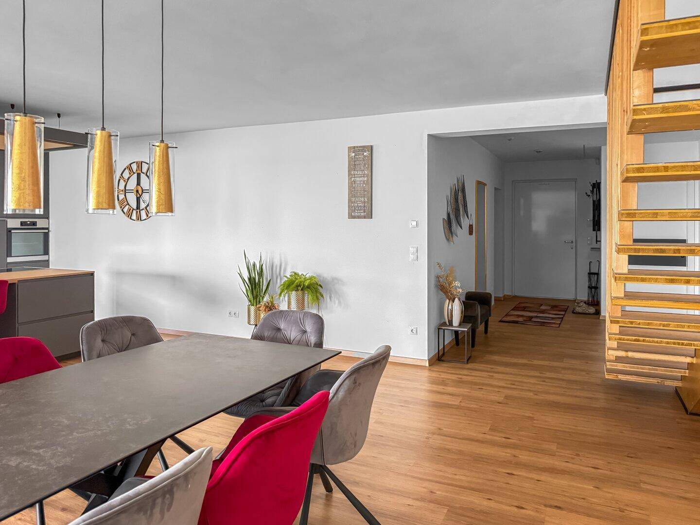 Offener Wohn-Essbereich mit Blick auf den Flur und die moderne Küche im Hintergrund.