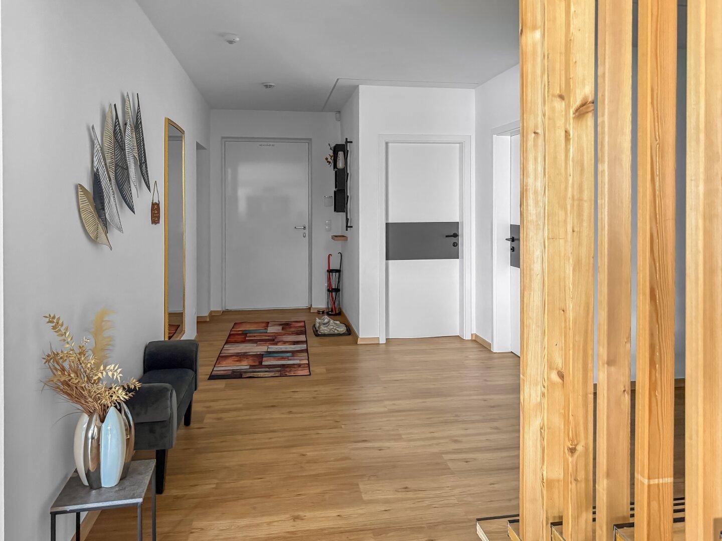 Heller Flur mit Holzboden, dekorativen Elementen und Zugang zu verschiedenen Räumen.