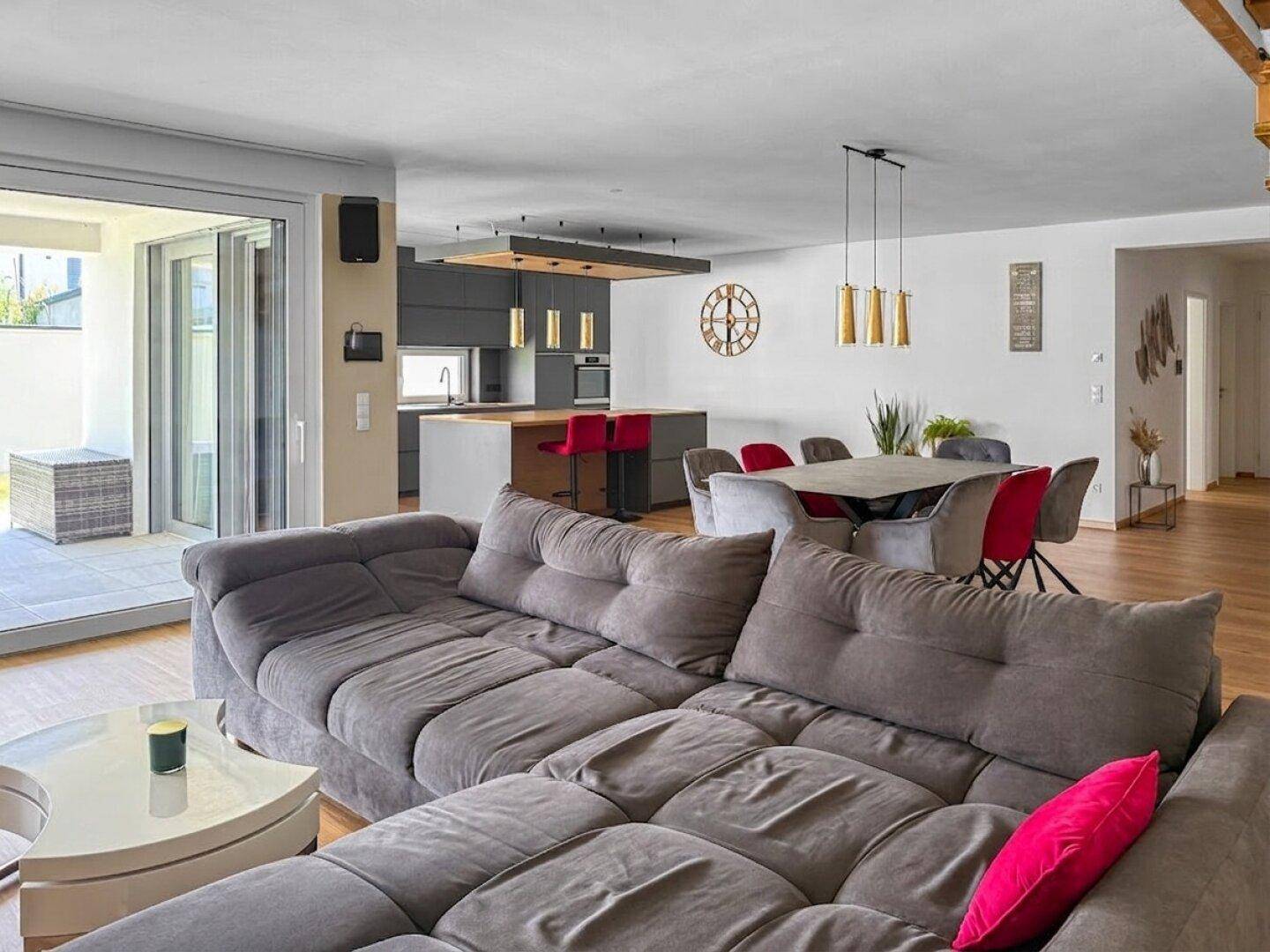 Geräumiges Wohnzimmer mit großem Ecksofa und Blick auf den Essbereich und die Küche.