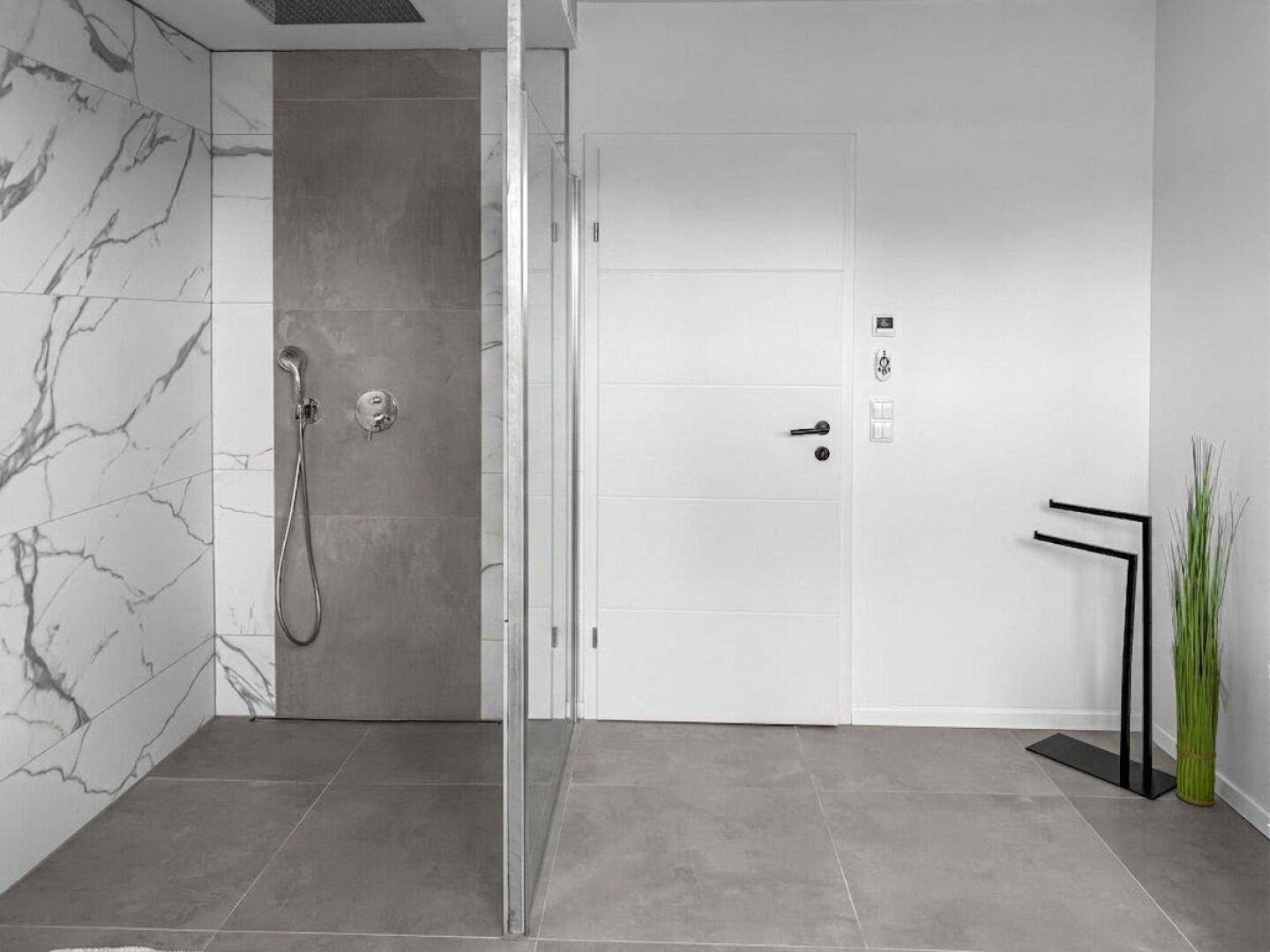 Geräumige Duschkabine mit Regendusche und modernen Fliesen in einem hellen Badezimmer.