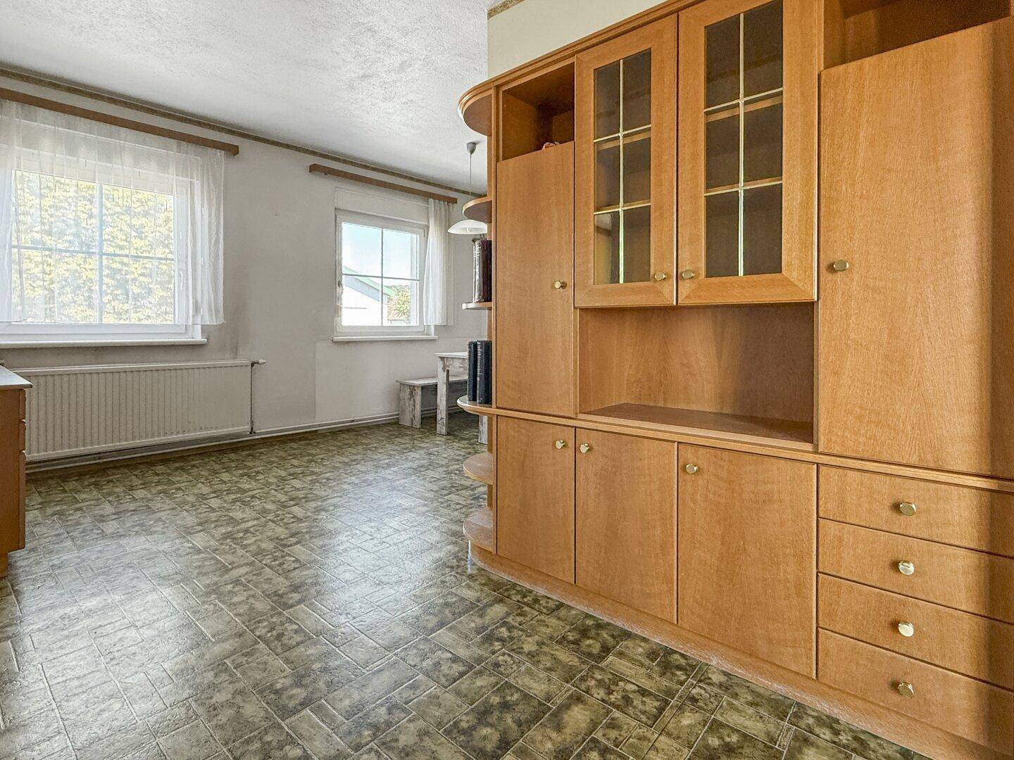 Essbereich mit Blick auf eine Holzküche und Fenster, die viel Tageslicht hereinlassen.
