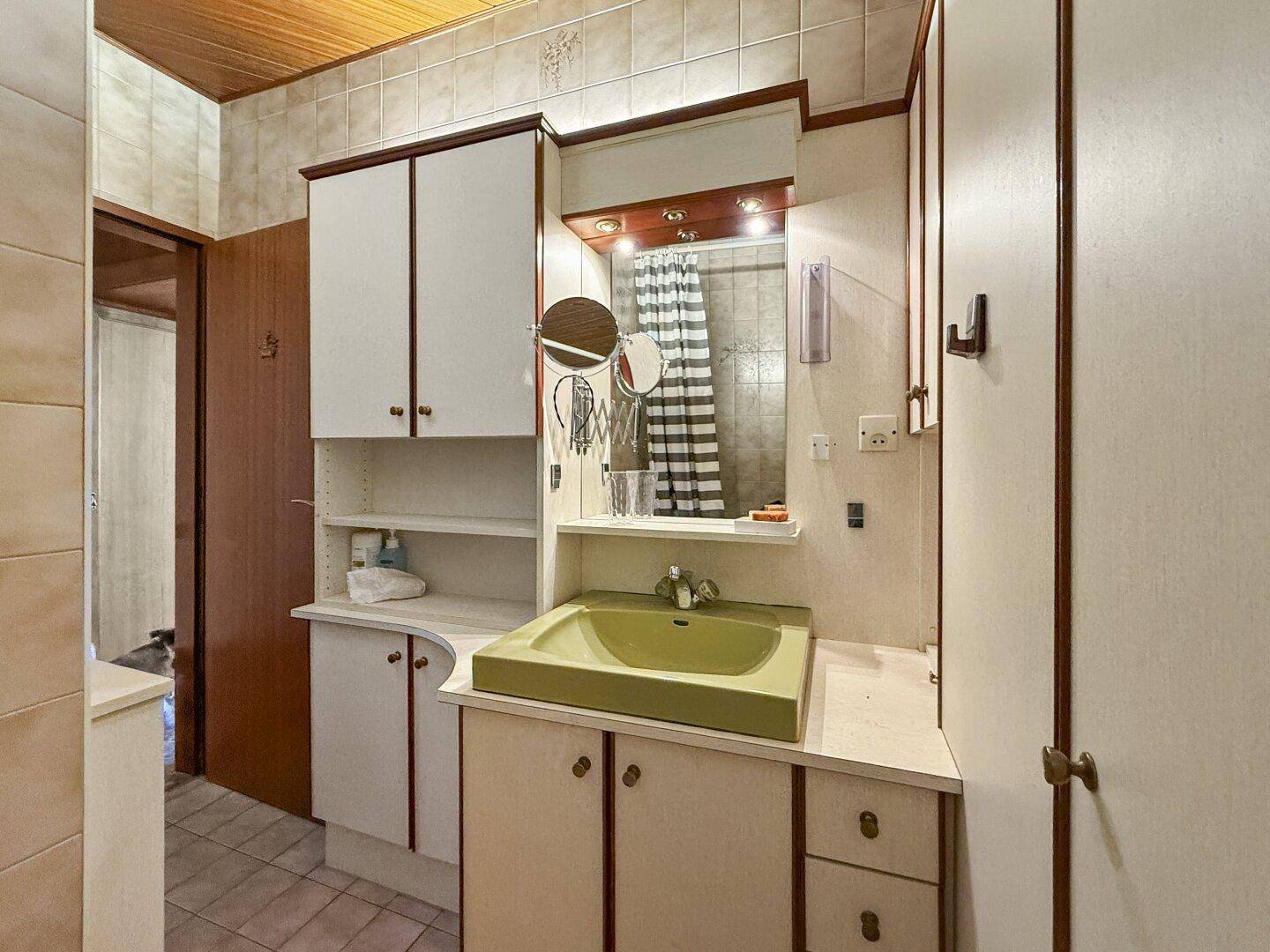 Badezimmer im 80er-Jahre-Stil mit grünem Waschbecken und Holzdecke.