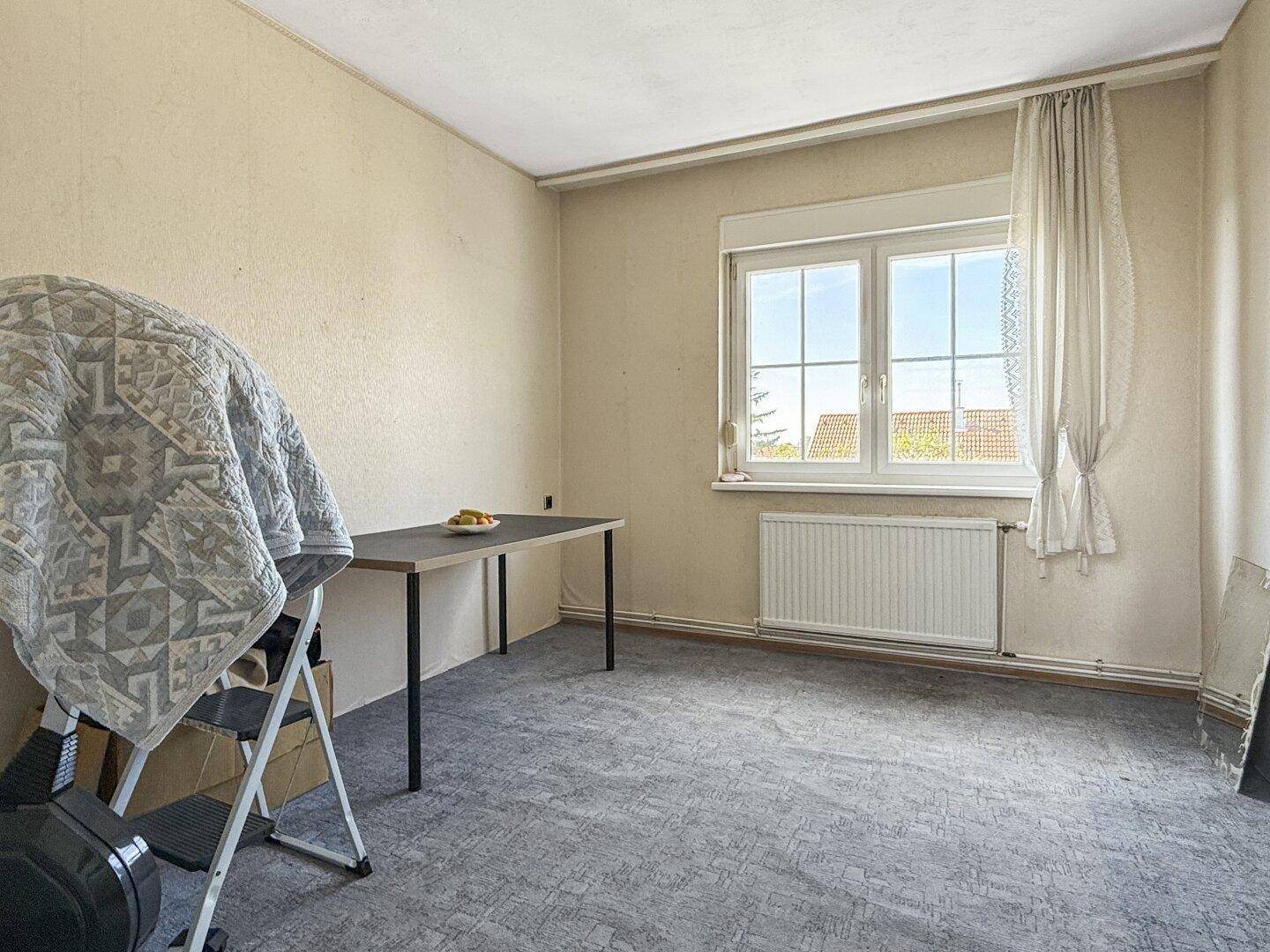 Schlafzimmer mit Teppichboden und einem einfachen Tisch, ideal als Arbeits- oder Gästezimmer.