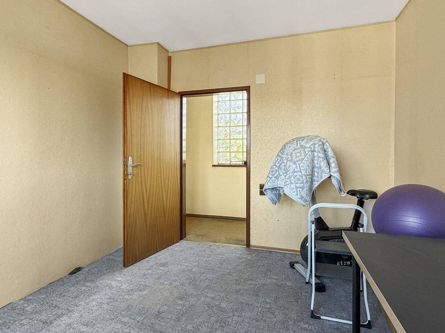 Schlafzimmer mit Teppichboden und Tür zu einem angrenzenden Raum, bietet vielseitige Nutzung.