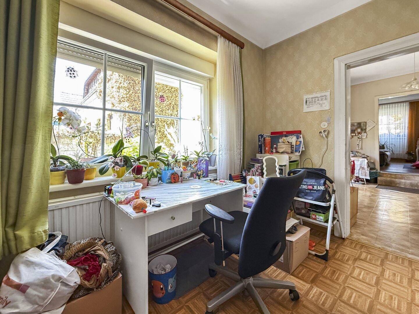 Helles Arbeitszimmer mit großem Fenster, Schreibtisch und Blick ins Grüne.