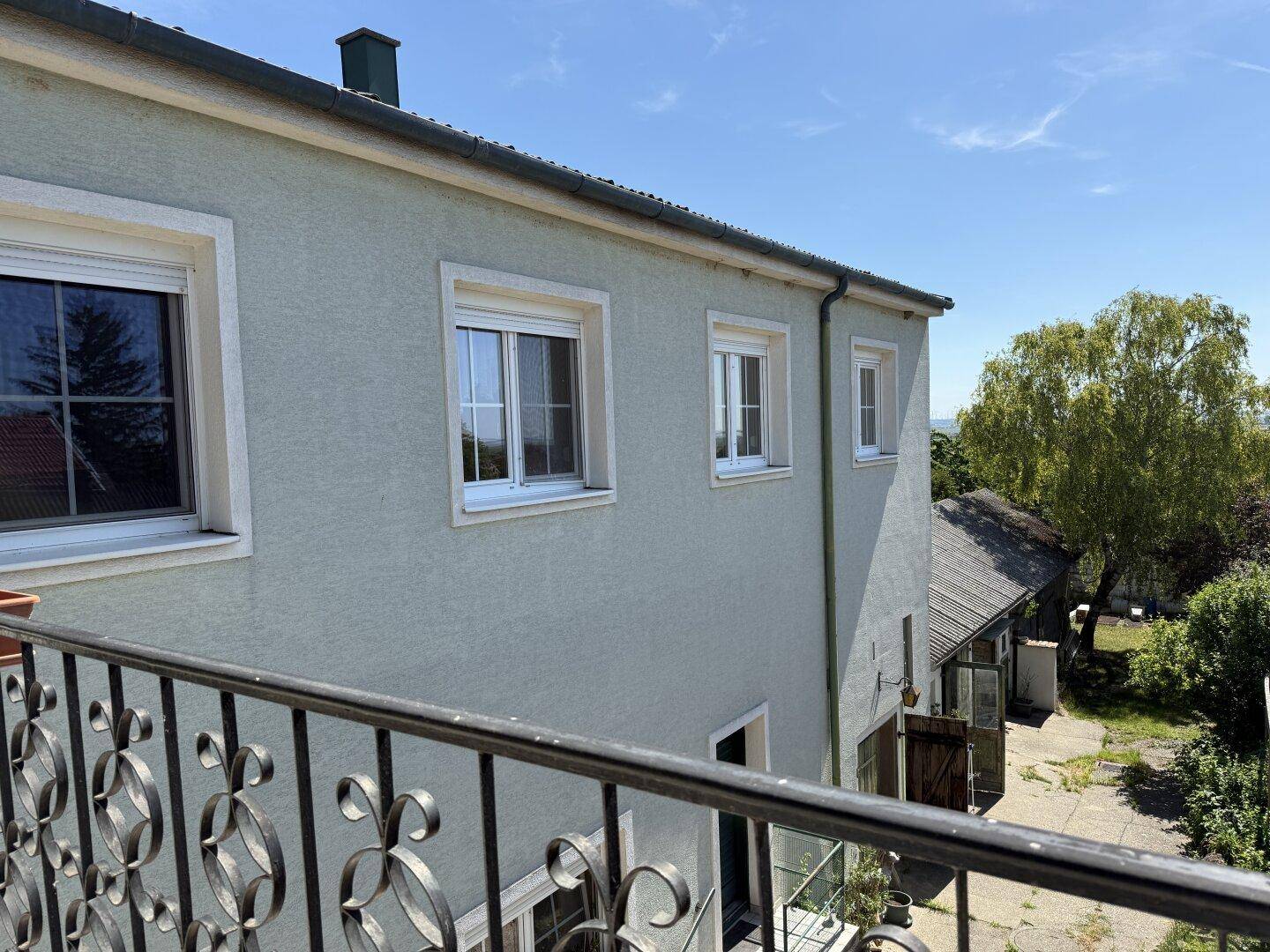 Blick vom Balkon auf die Gebäudefassade und die umliegende grüne Landschaft.