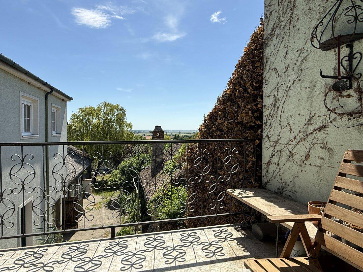 Balkon mit schmiedeeisernem Geländer und Holzsitzgelegenheiten, bietet einen weiten Blick.