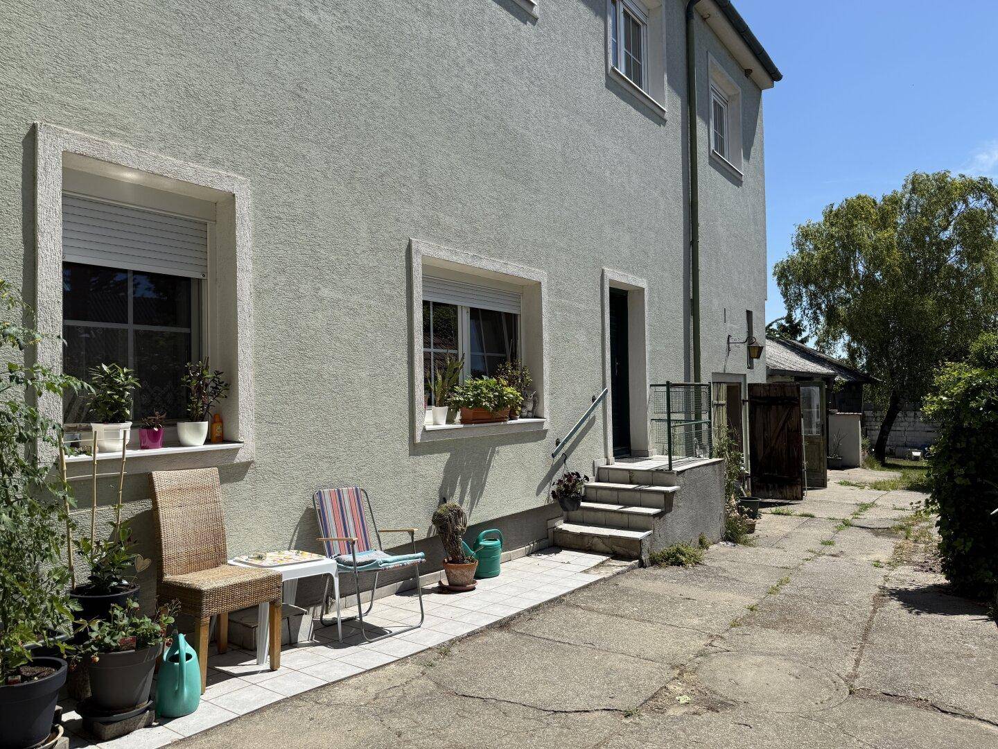 Kleine Terrasse am Haus mit Sitzgelegenheiten und Blick auf den Gartenbereich.