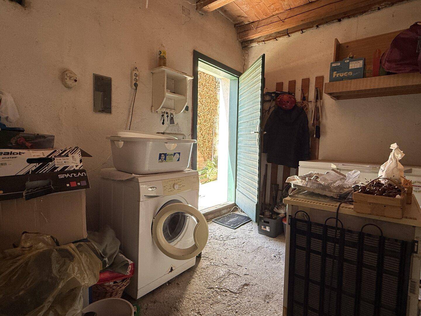 Hauswirtschaftsraum mit Waschmaschine, Gefriertruhe und Zugang zum Außenbereich.