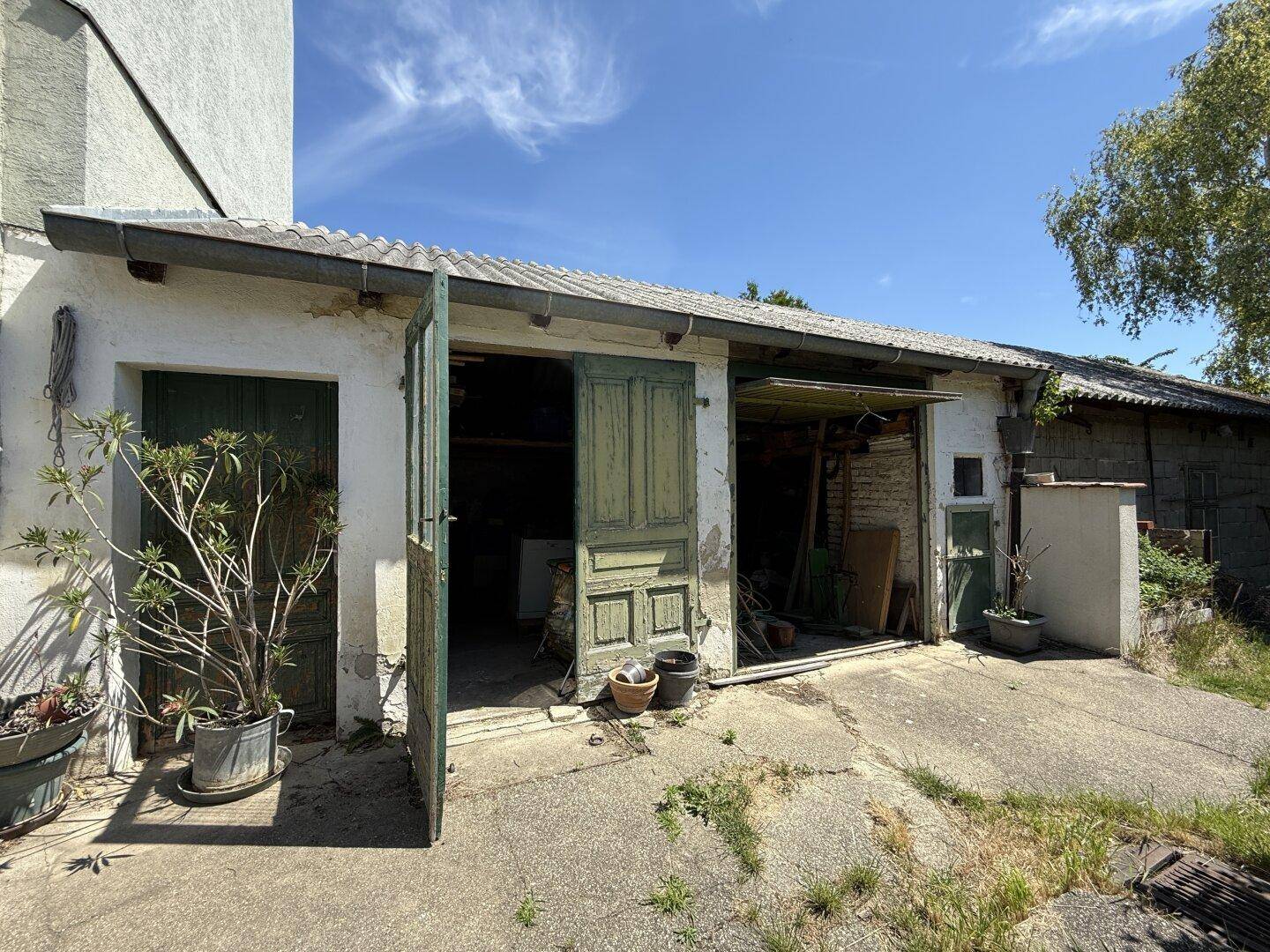 Offene Garage mit Holztoren und Platz für Fahrzeuge oder Lagerung.