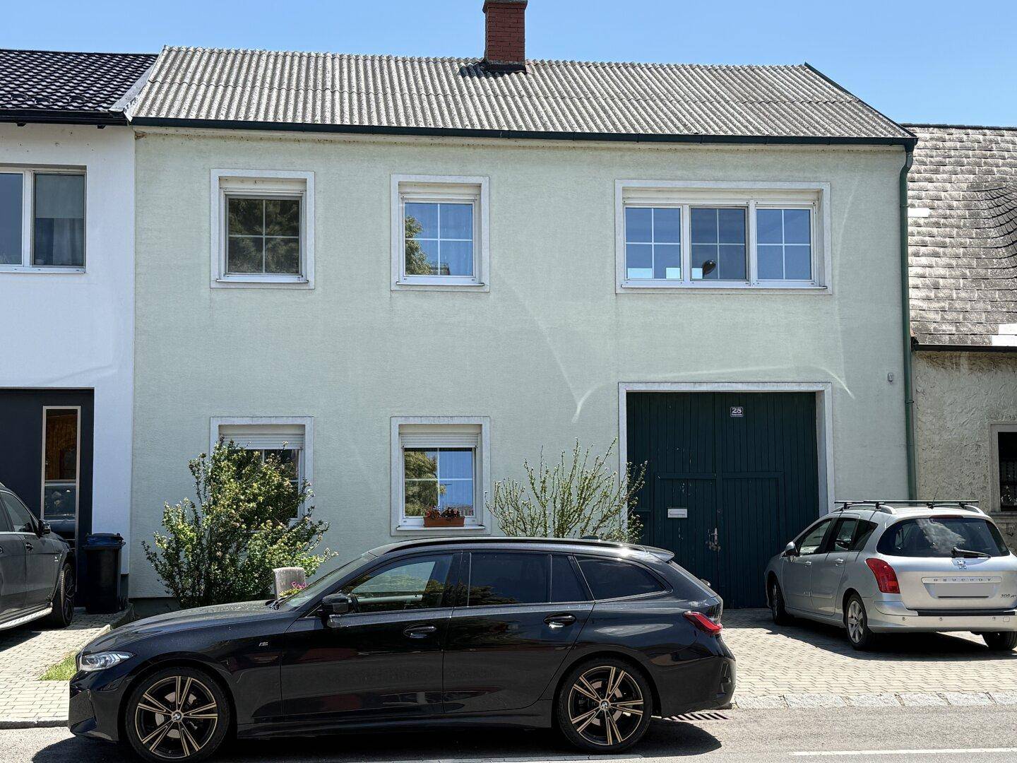 Fassade eines Wohnhauses mit mehreren Fenstern und einem Garagentor.