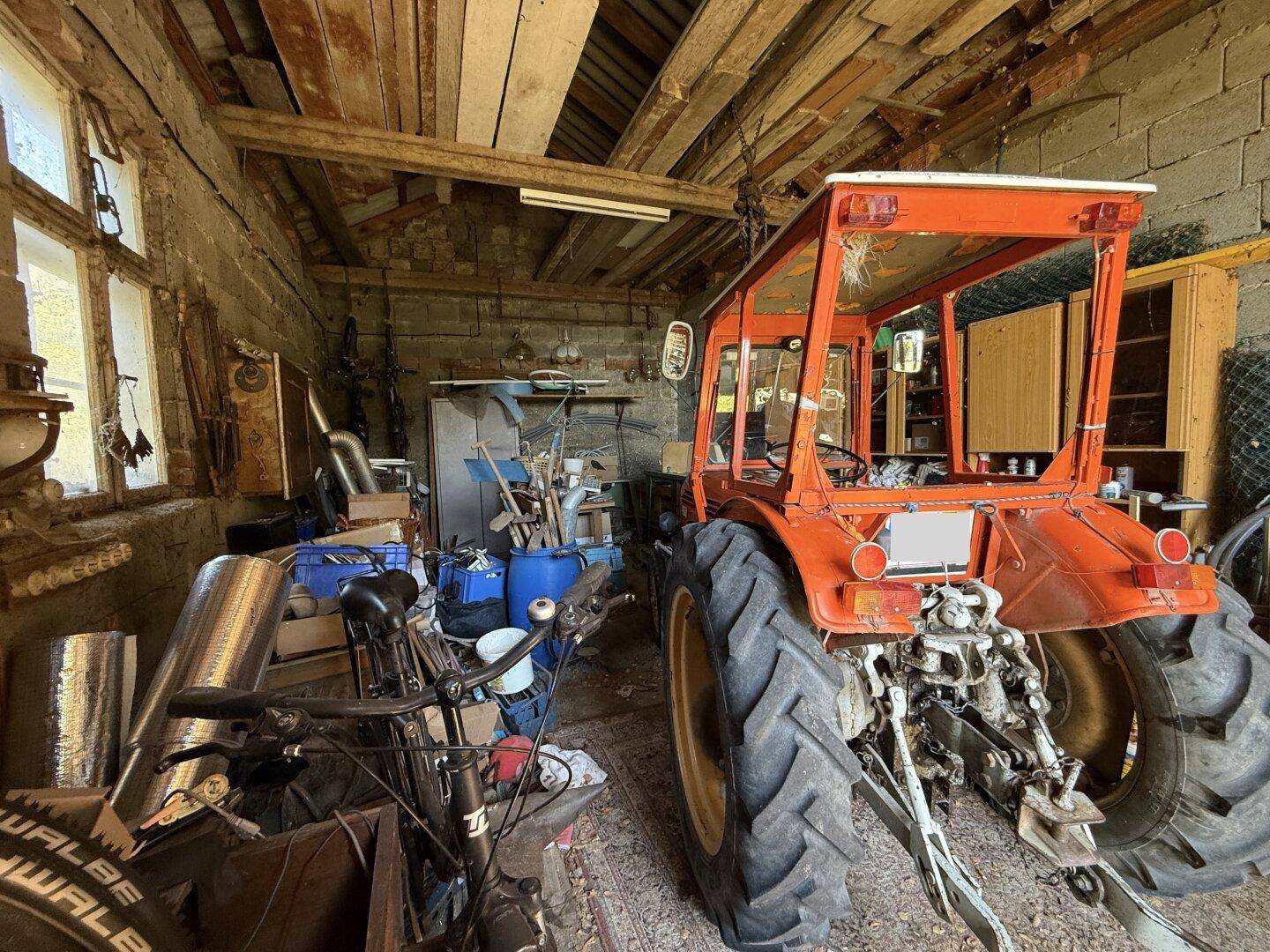 Geräumige Scheune mit einem Traktor und verschiedenen landwirtschaftlichen Geräten.