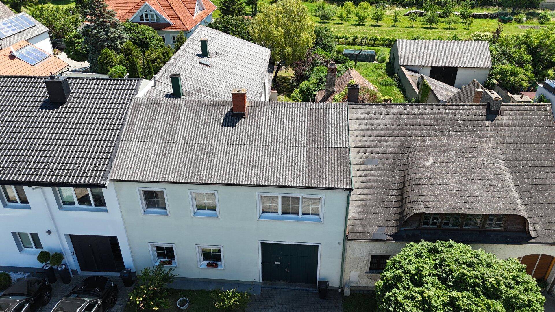 Luftaufnahme der Hausfassade mit Dächern und umliegenden Gebäuden.