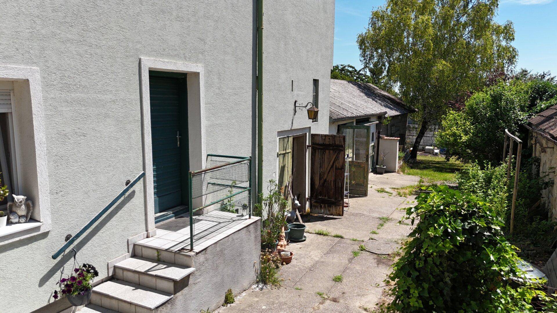 Eingangsbereich des Hauses mit Treppe, grüner Tür und Zugang zum gepflegten Hofbereich.