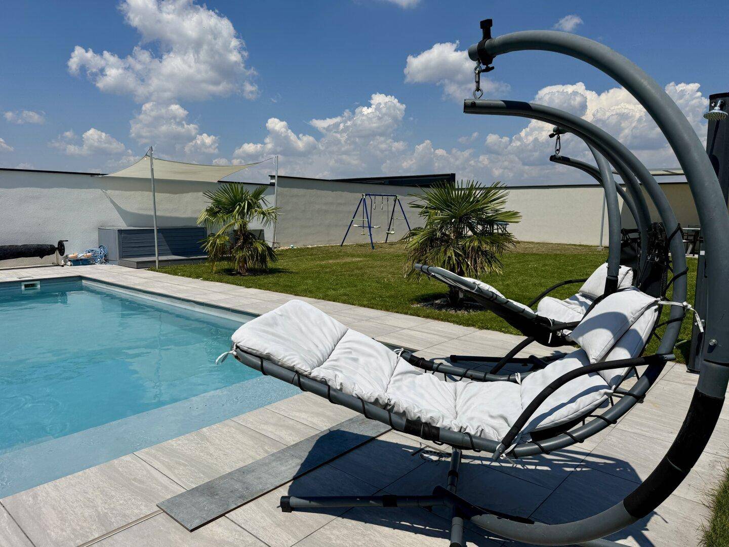 Moderner Poolbereich mit einzigartigen Hängesesseln und sonniger Atmosphäre.