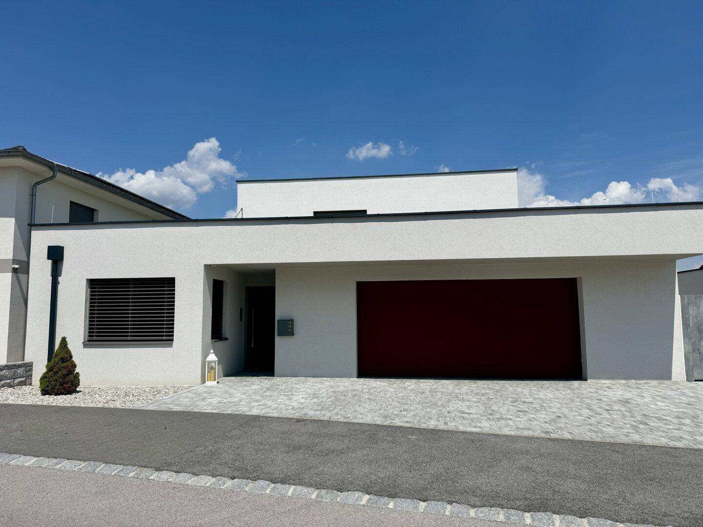 Moderne Hausfassade mit Garage, gepflasterter Auffahrt und minimalistischem Design.