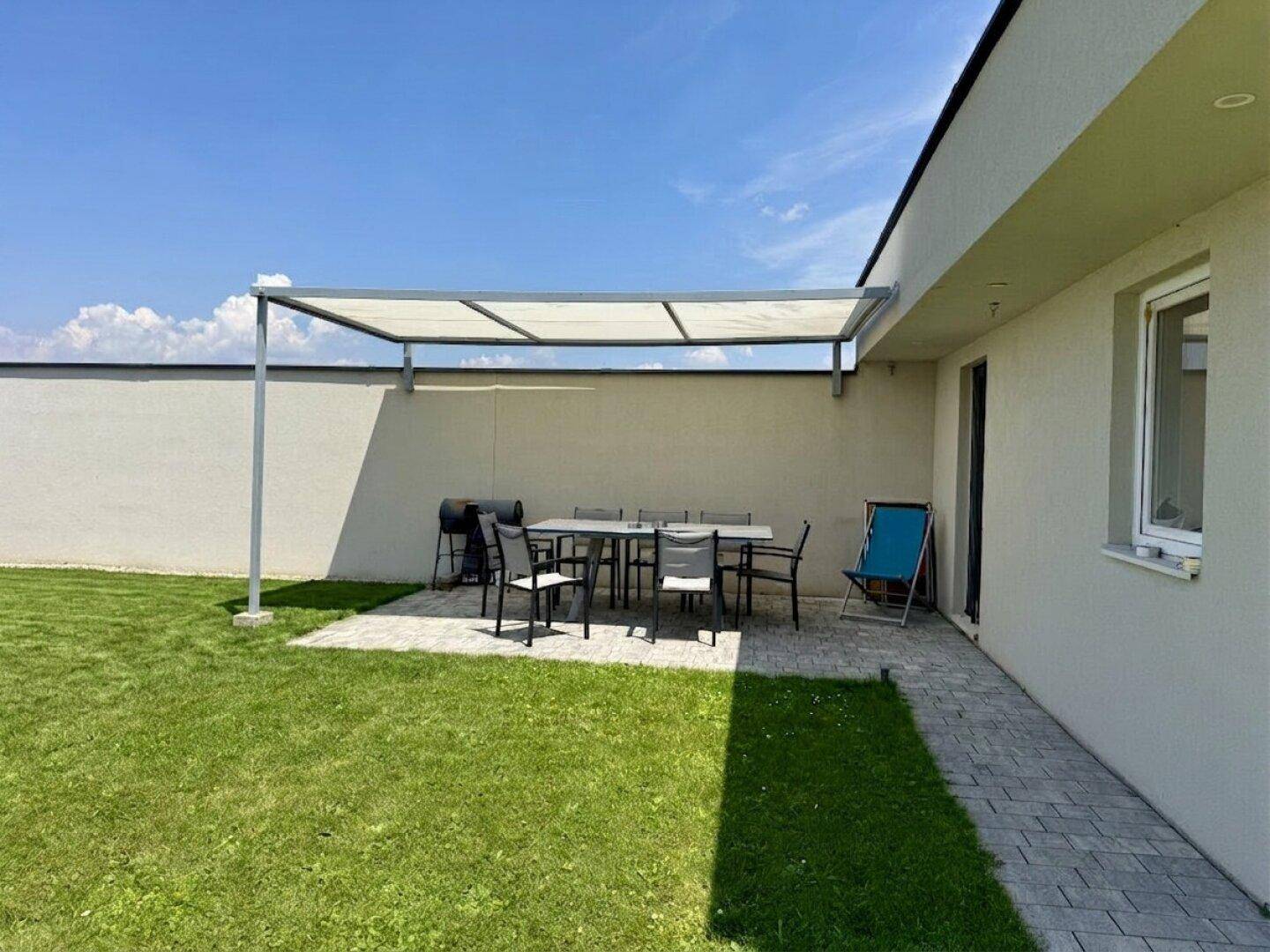 Überdachte Terrasse mit Esstisch und Grillbereich, ideal für Mahlzeiten im Freien.