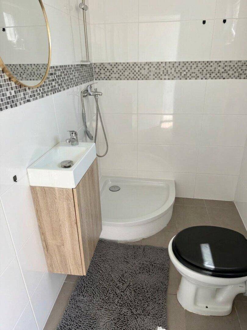 Modernes Badezimmer mit Duschkabine, Waschbecken und Wandspiegel.