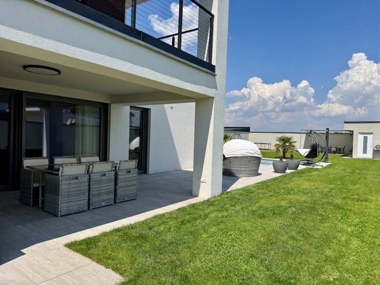 Überdachte Terrasse mit Esstisch und Blick auf den Garten und Poolbereich.