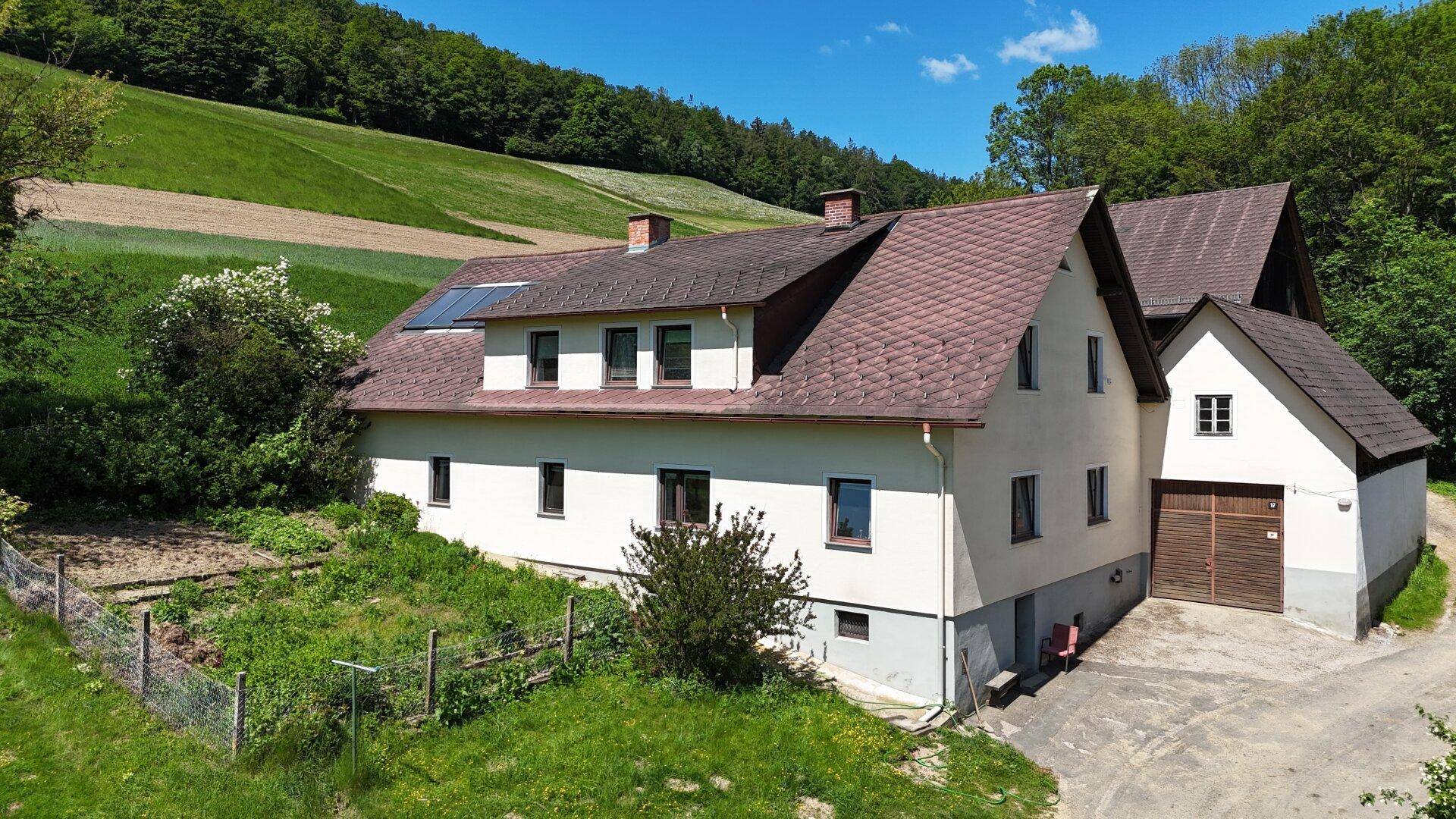 Nahaufnahme des Haupthauses mit Gartenbereich und Photovoltaikanlage auf dem Dach.