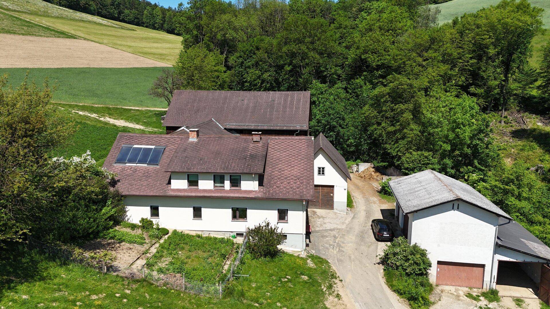 Luftaufnahme des Wohnhauses mit angrenzendem Garten und weiteren Nebengebäuden in ländlicher Umgebung.