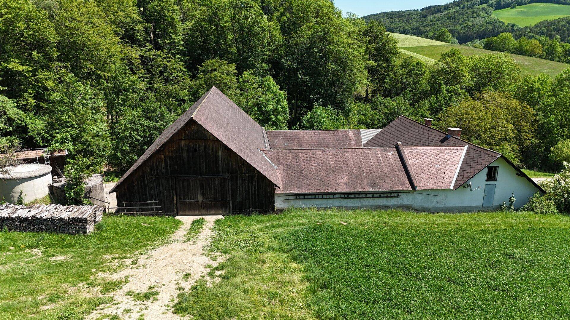 Ländliches Anwesen mit großen Scheunen und Wohnhaus, umgeben von üppiger Natur.