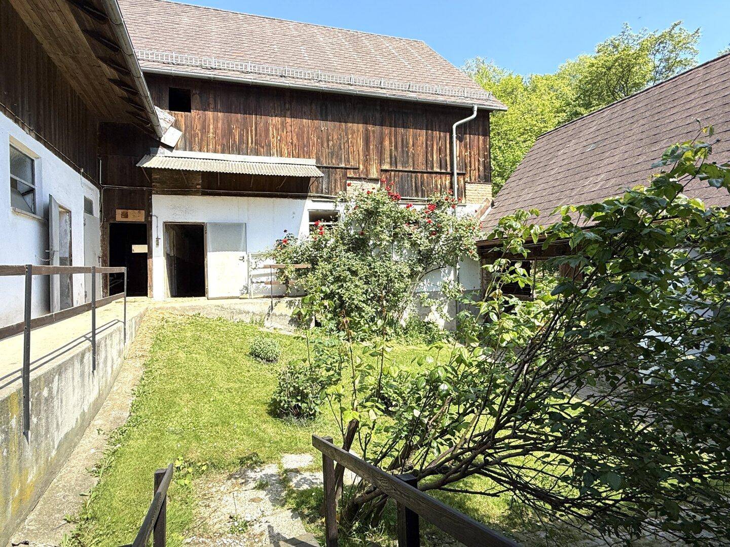 Sonniger Innenhof mit gepflegtem Rasen und Holzbauten, die den ländlichen Charme unterstreichen.