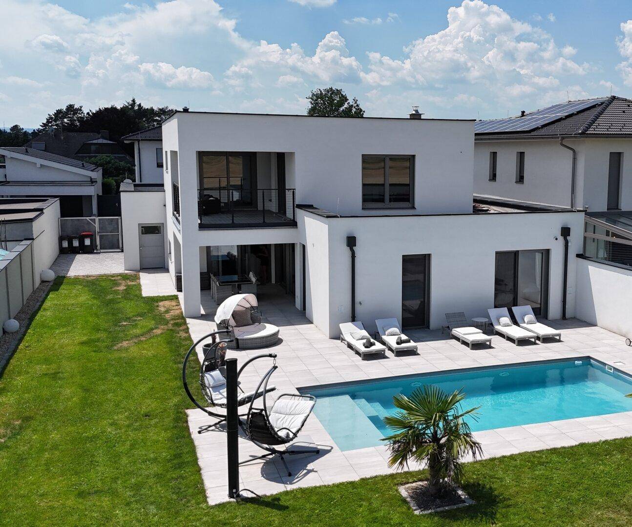 Gesamtansicht des modernen Hauses mit Pool, Garten und großzügiger Terrasse.