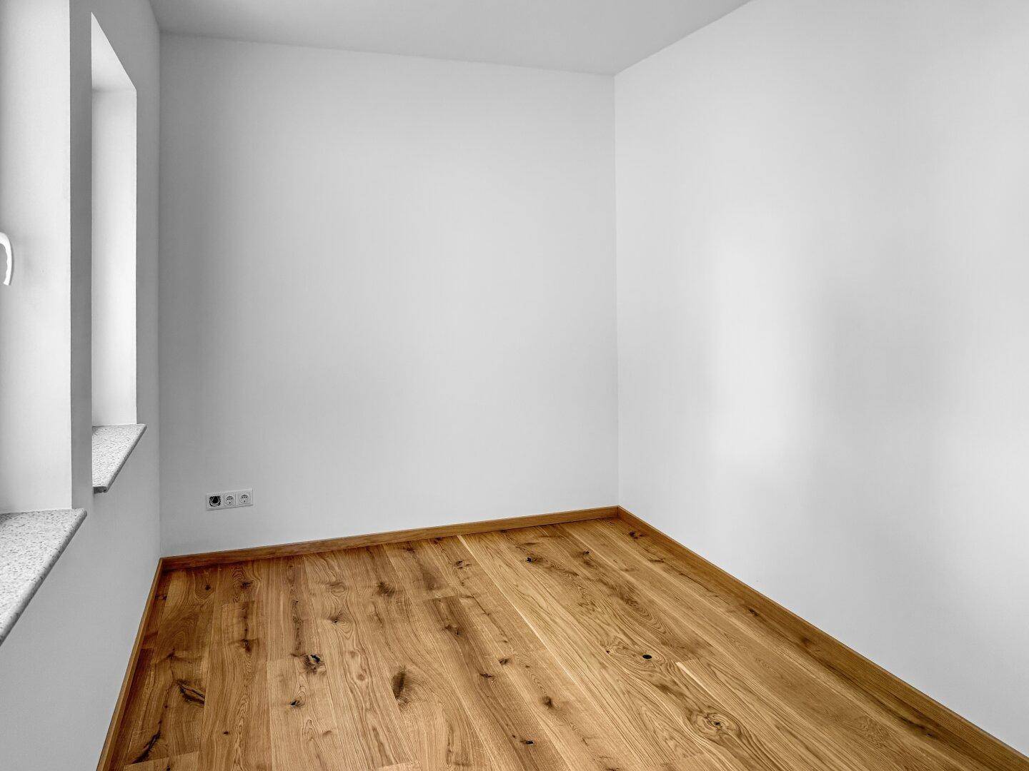 Ruhiges Schlafzimmer mit Holzboden und Fenster, ideal für erholsame Nächte.