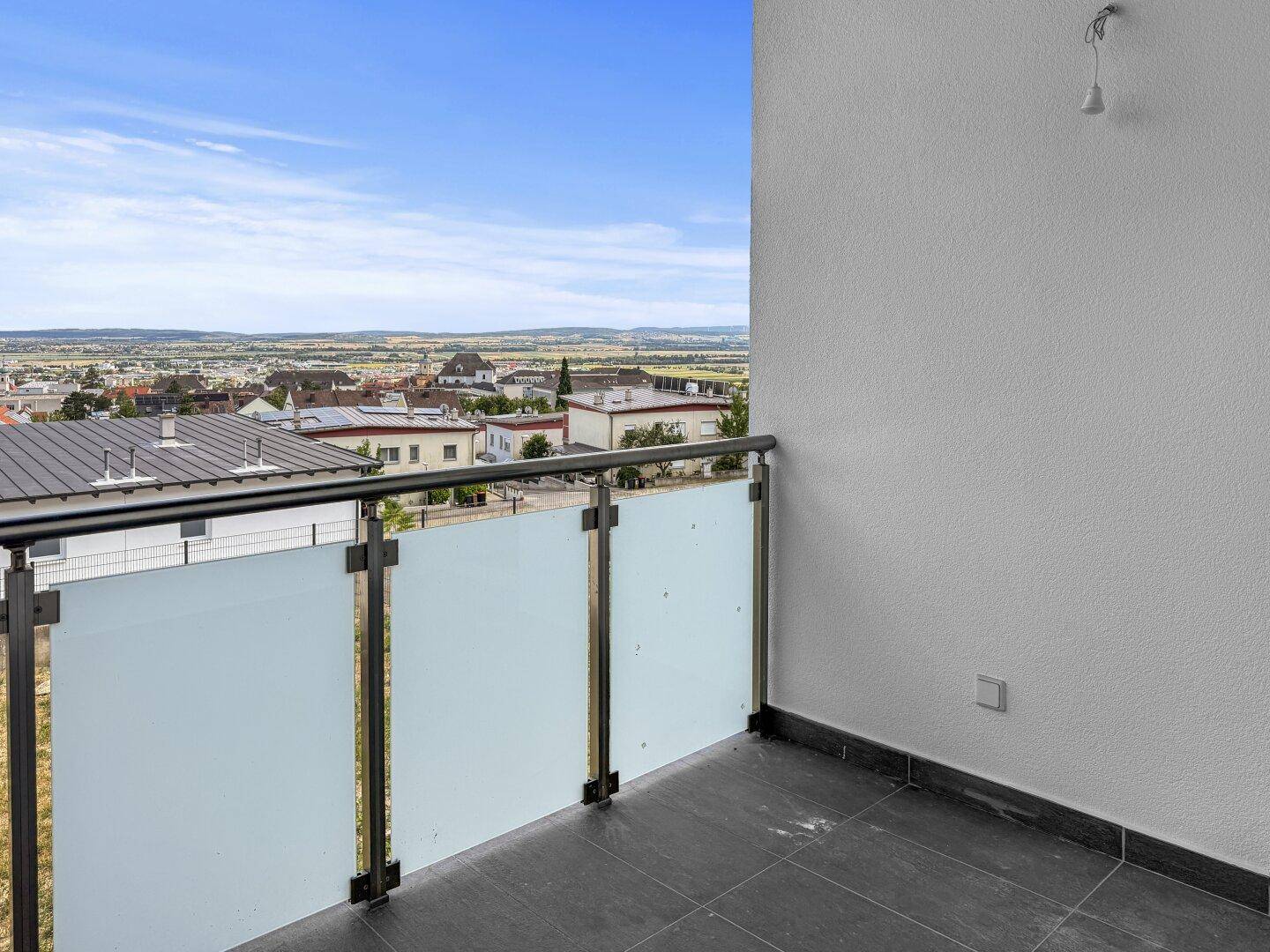 Balkon mit Glasgeländer und weitem Blick über die umliegende Landschaft und Stadt.