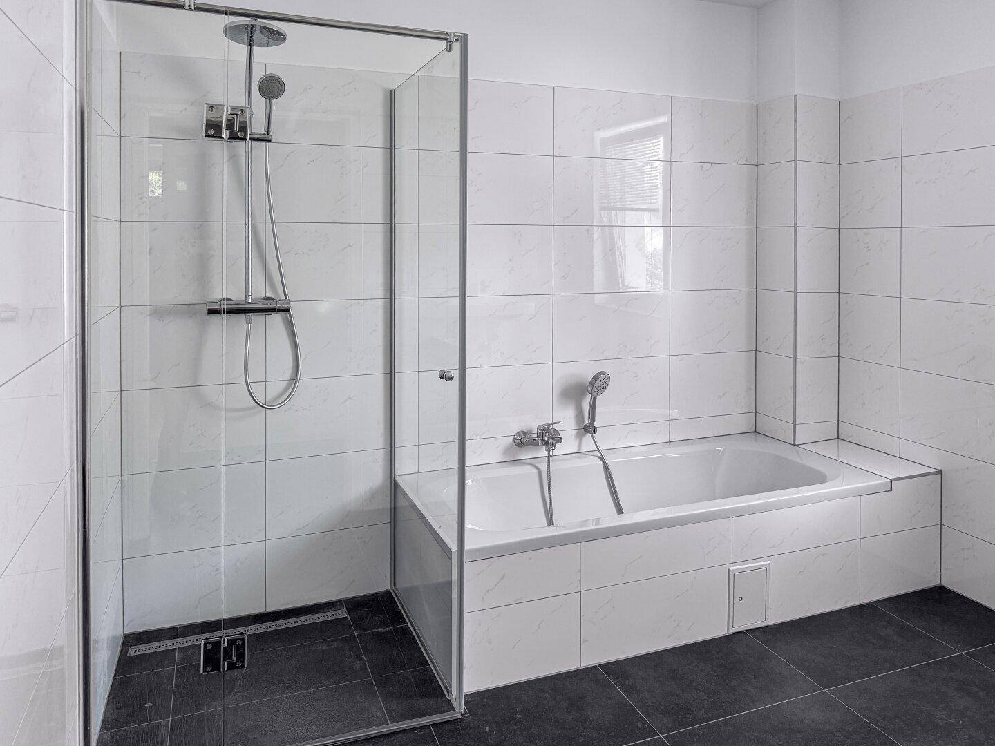 Modernes Badezimmer mit Badewanne, Dusche und weißen Fliesen an den Wänden.