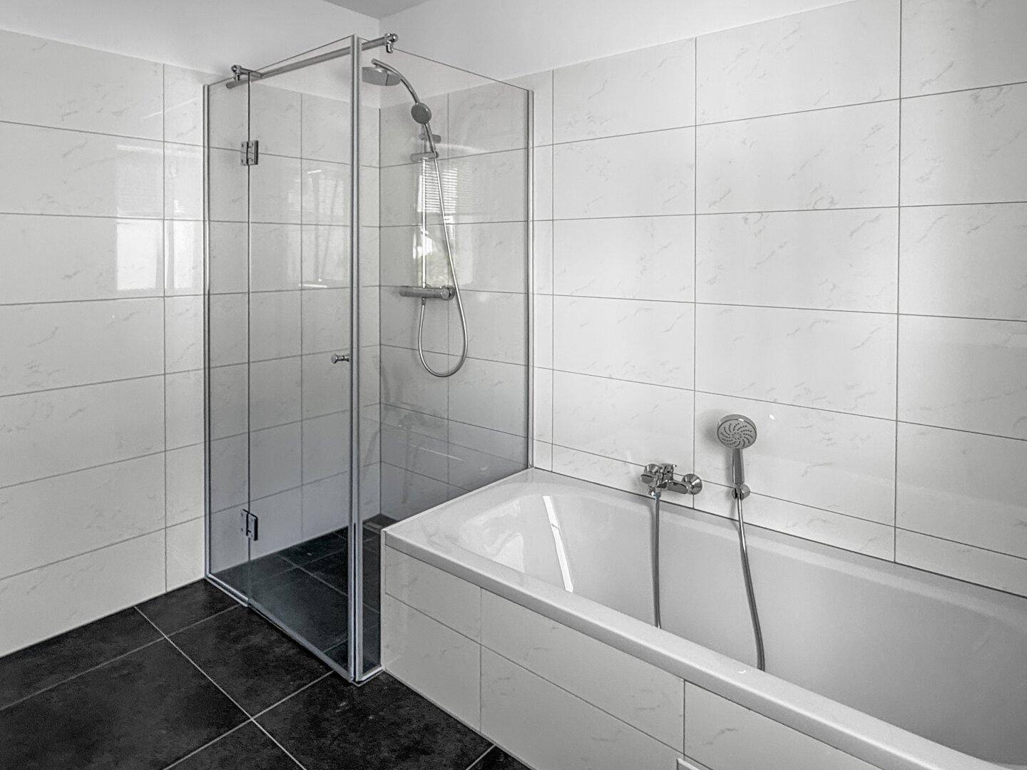 Modernes Badezimmer mit Badewanne und separater Glasdusche, hell gefliest.