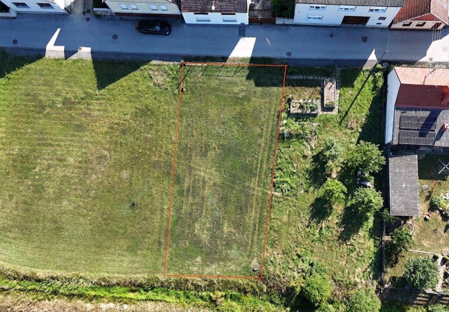 Vogelperspektive eines umrandeten Grundstücks in ländlicher Umgebung mit angrenzenden Häusern und Straße.