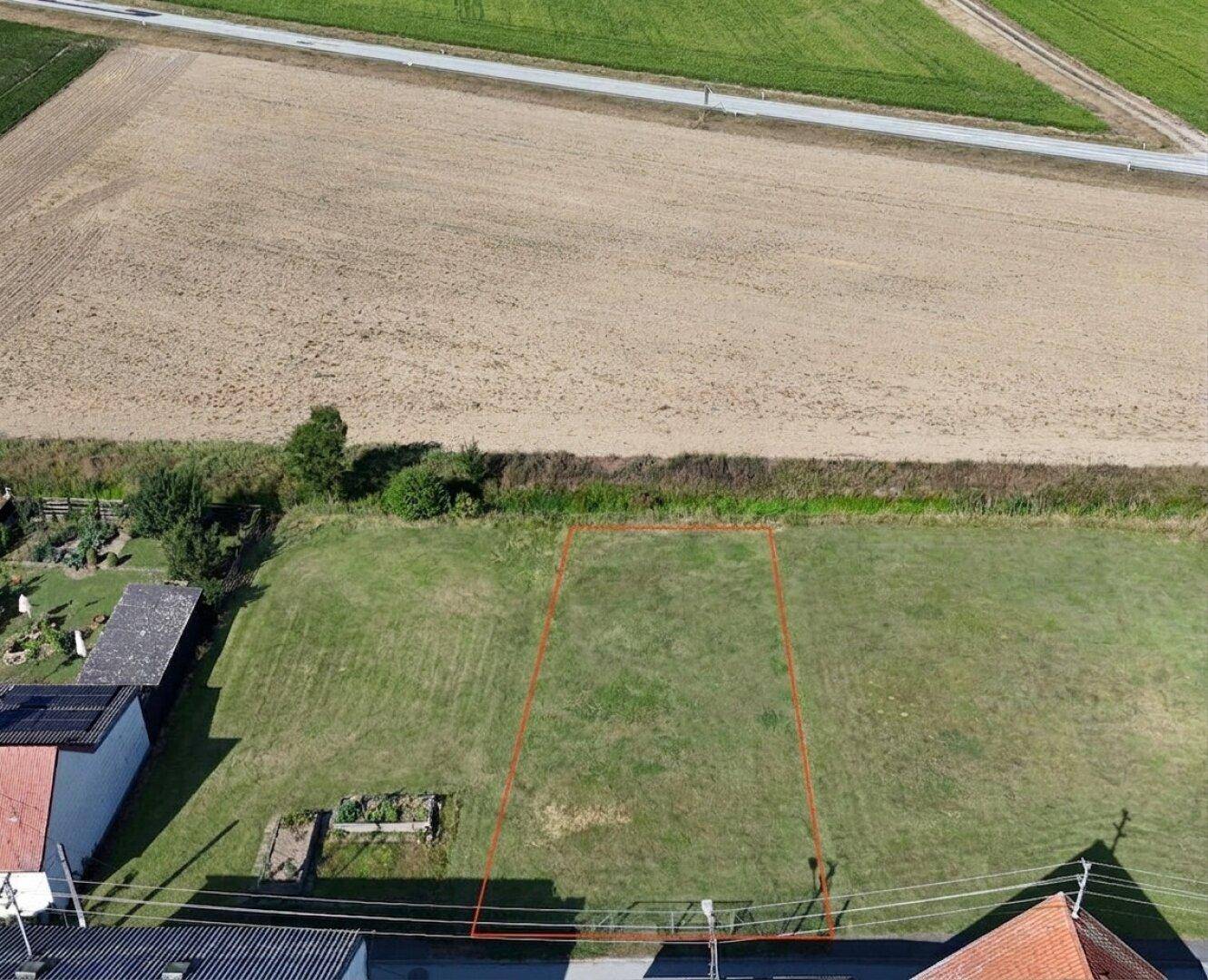 Luftaufnahme eines Grundstücks mit roter Umrandung, umgeben von Feldern und angrenzenden Häusern.