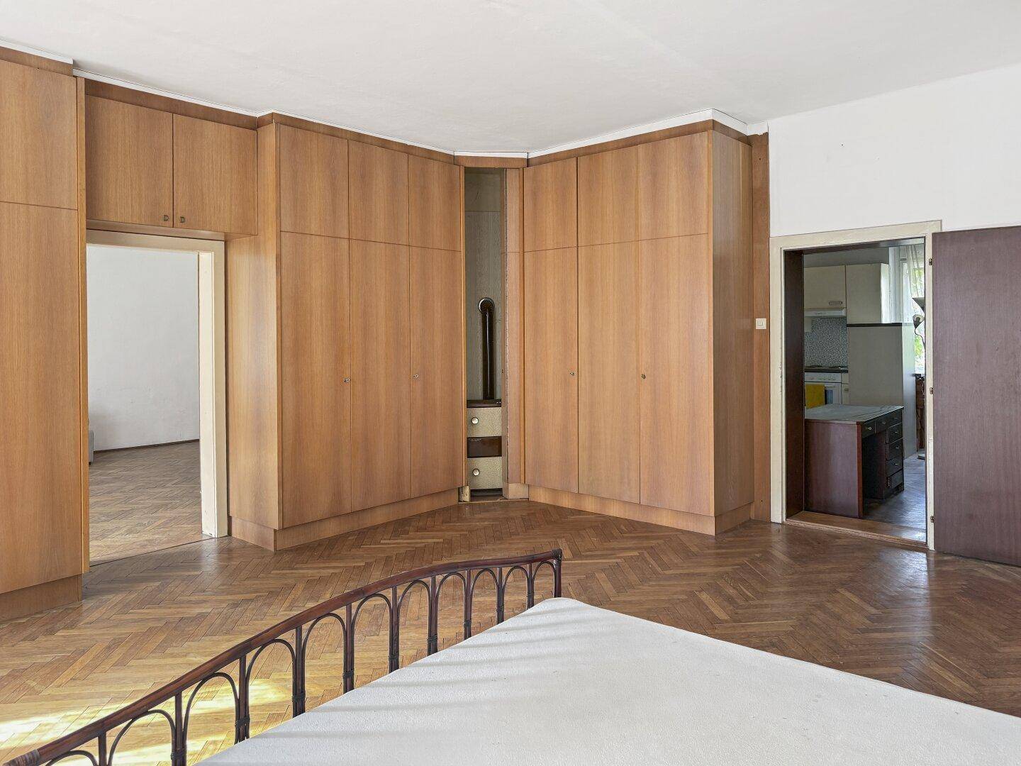 Schlafzimmer mit umfangreichen Einbauschränken aus Holz und Zugang zu weiteren Räumen.