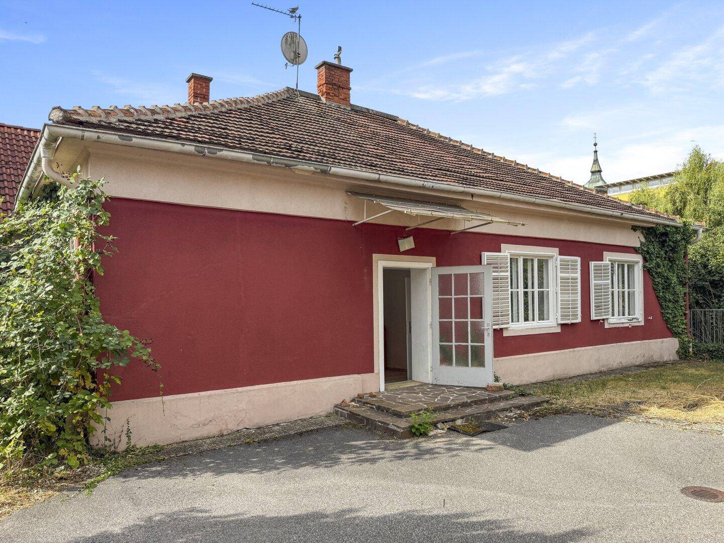 Rückansicht des Hauses mit offener Tür, Fenstern und weißen Fensterläden.
