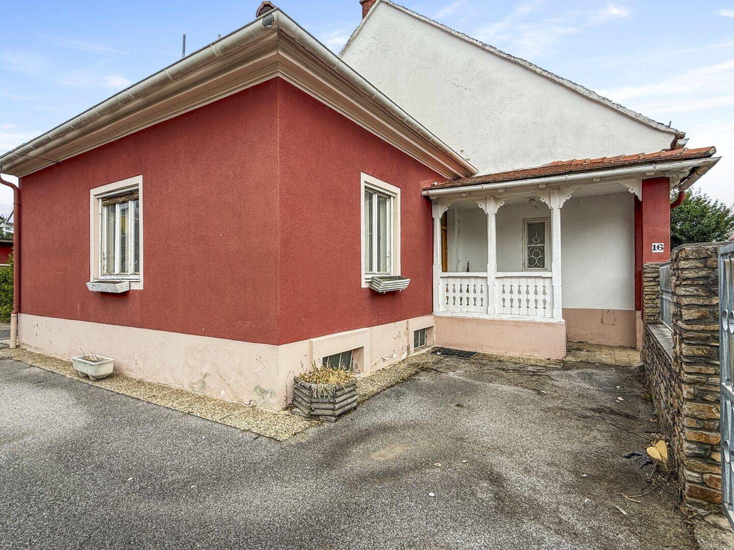 Seitenansicht des roten Hauses mit einem überdachten Eingangsbereich und kleiner Veranda.