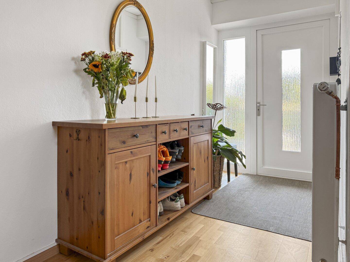 Heller Eingangsbereich mit Holzschuhschrank, Spiegel und Holzboden.