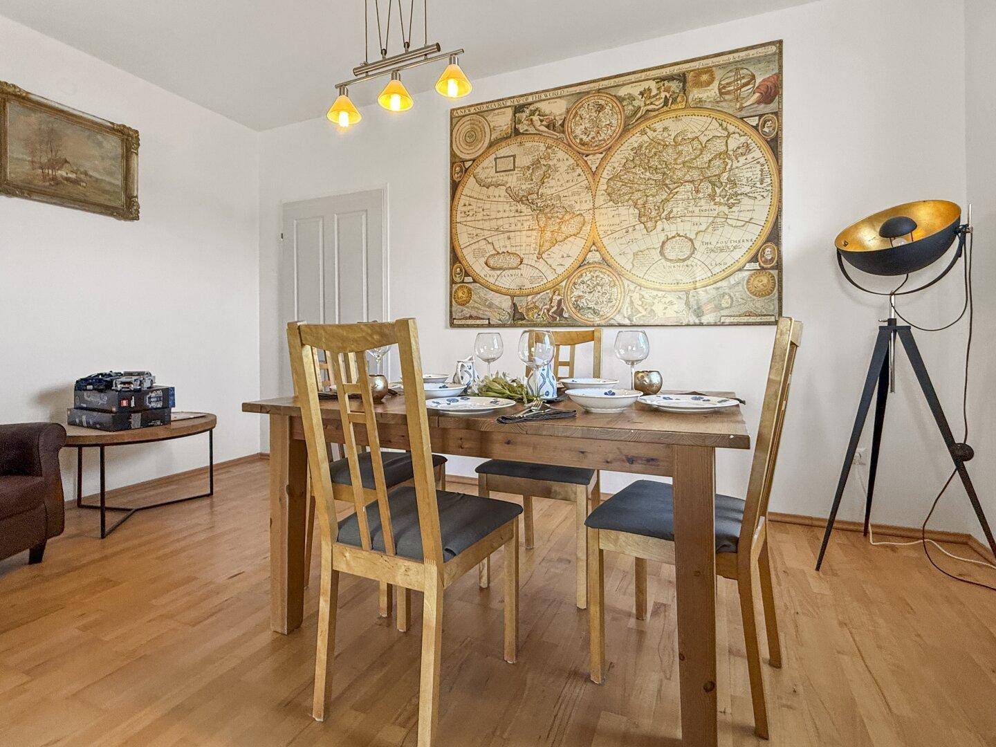 Essbereich mit Holztisch, Stühlen und einer großen Weltkarte als Wanddekoration.